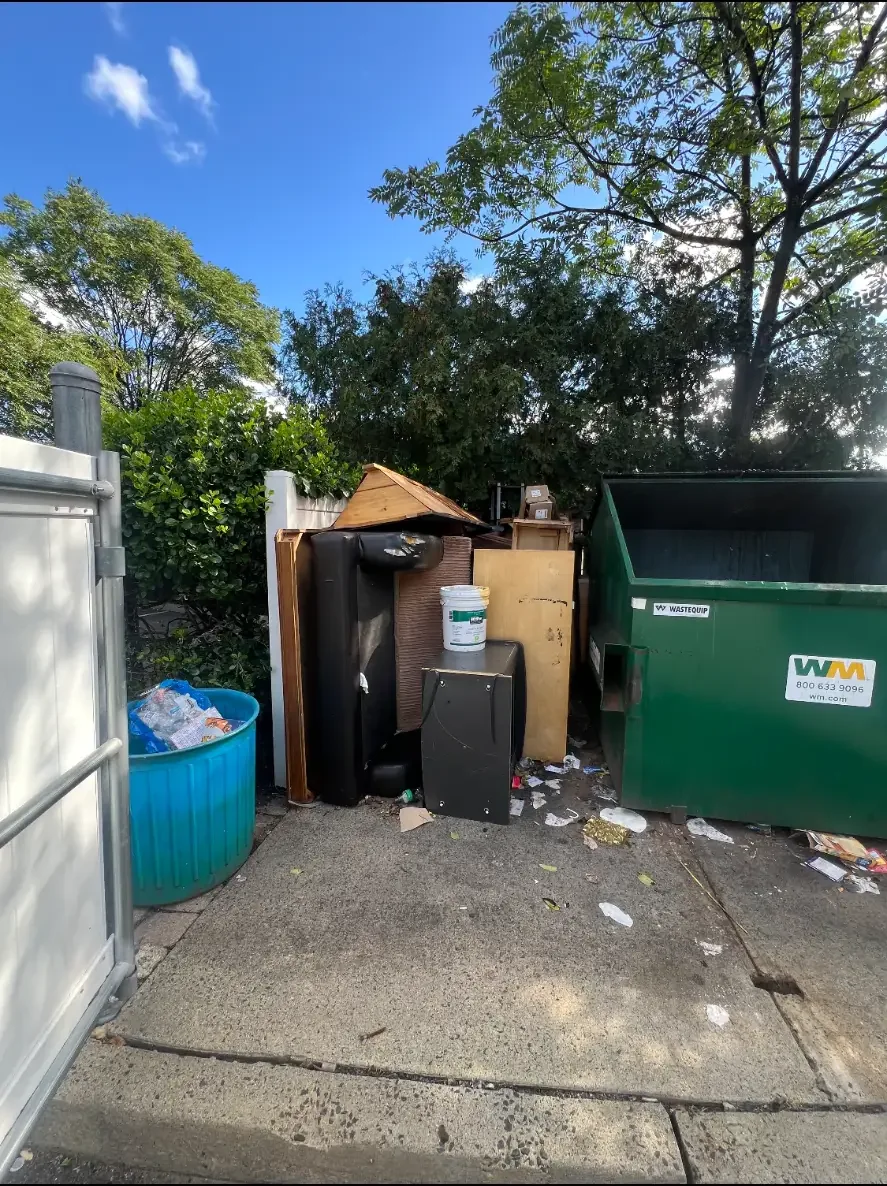 Furniture and unwanted items set out near a dumpster